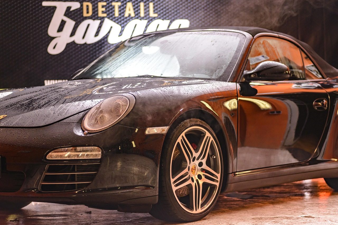 Professional automotive detailing workshop with technician performing specialized service on luxury vehicle